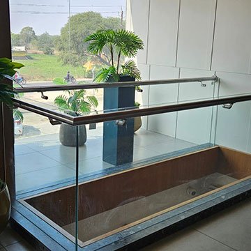 Toughened glass balcony railing with a stainless steel handrail installed in Anand