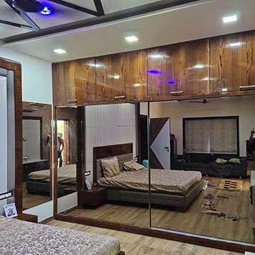 Mirror finish sliding wardrobe shutters fitted in a bedroom in Anand